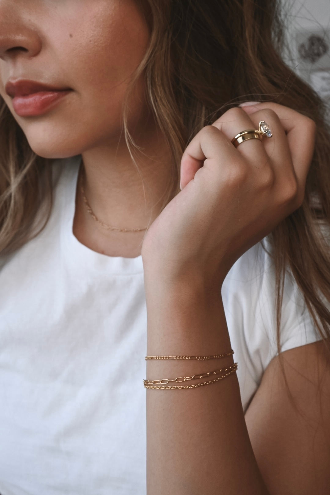 Woman wearing a white T-shirt and three gold fused jewellery bracelets